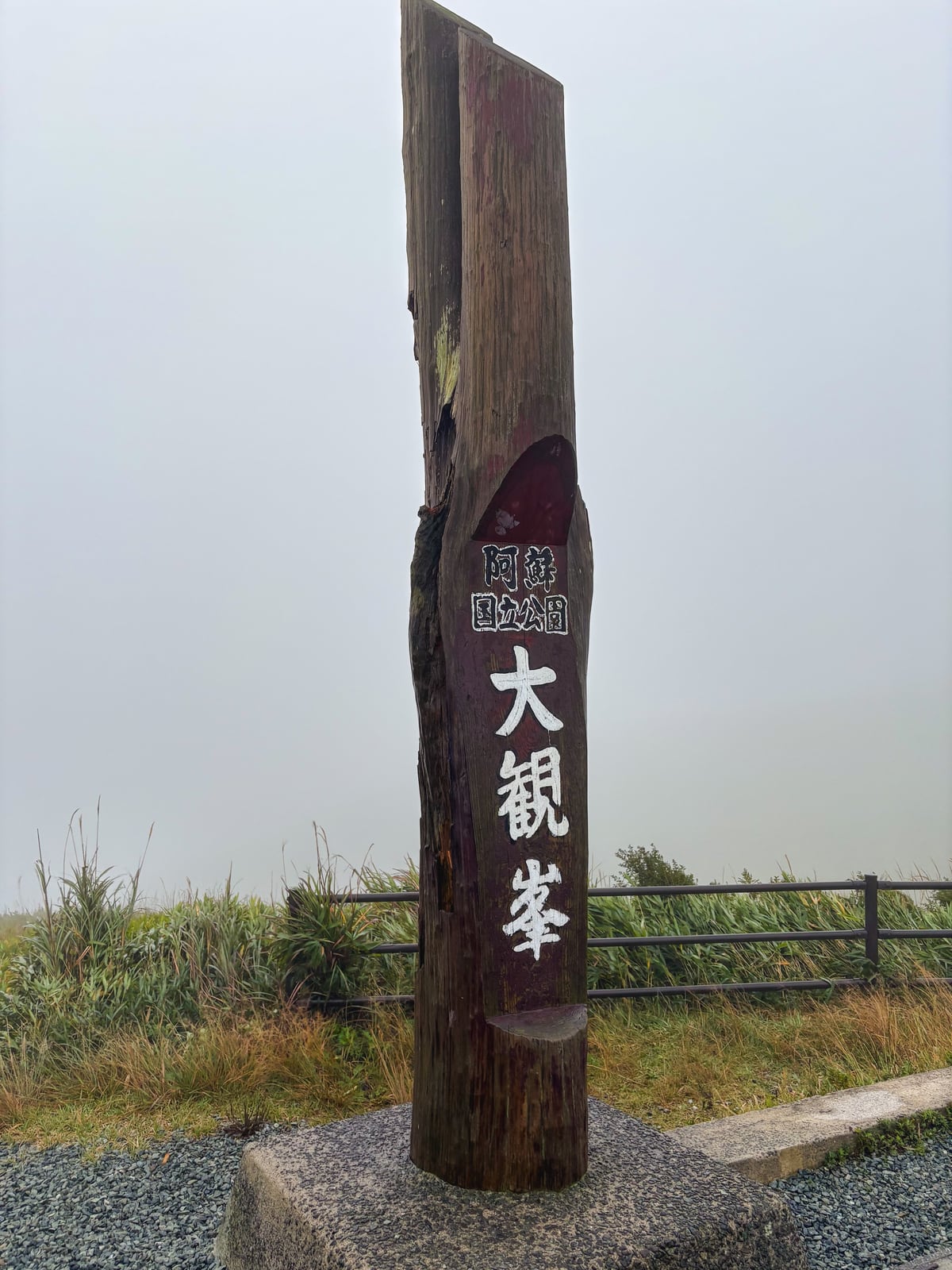 霧の中に立つ阿蘇大観峰の木製標柱