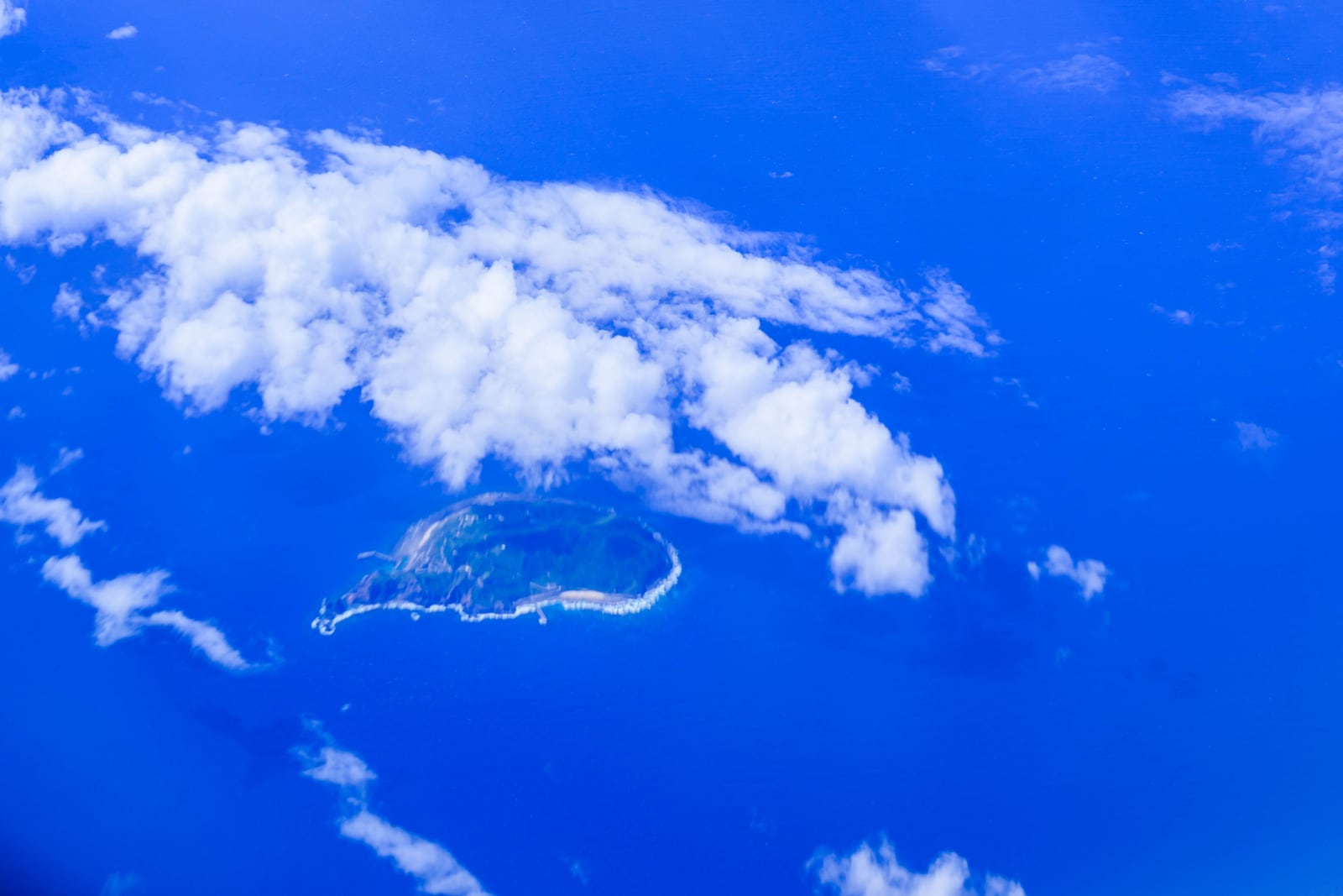 飛行機の窓から見た雲に囲まれた沖縄の島