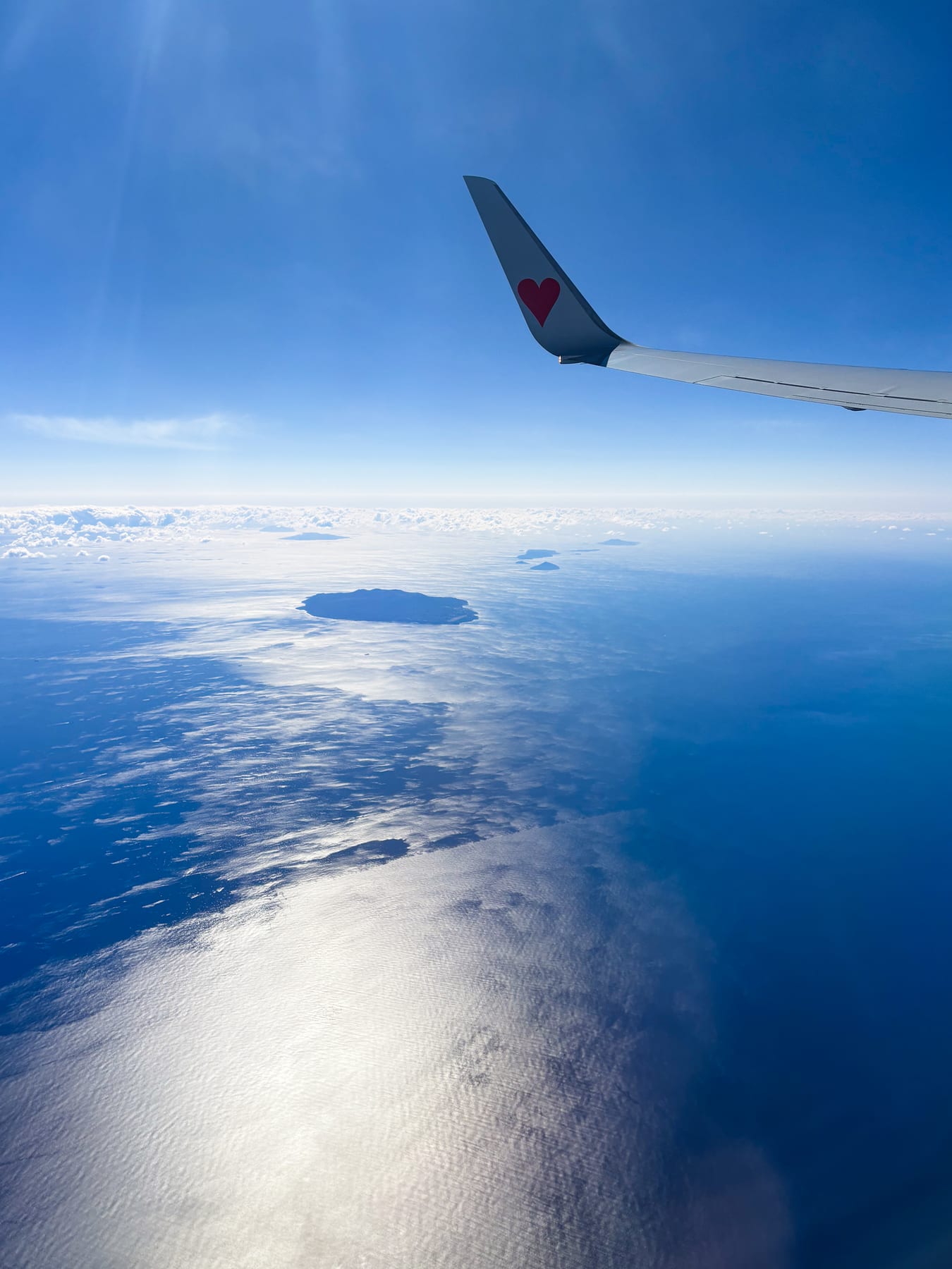 下地島へ向かう飛行機の窓から見た青い海と翼