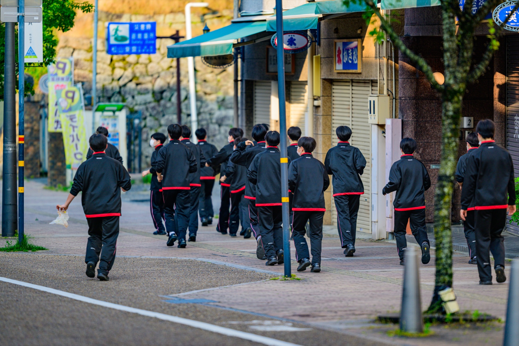 早朝の大街道でごみを拾いながら走る学生たち