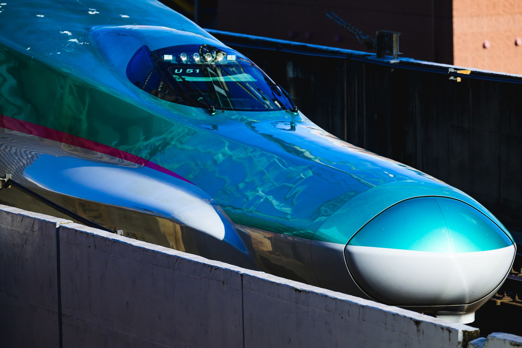 青緑色の車体が光を反射する新幹線