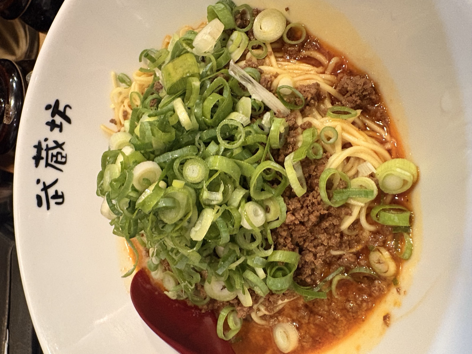 武蔵坊の器に盛られ、青ねぎとひき肉が載った汁なし担々麺