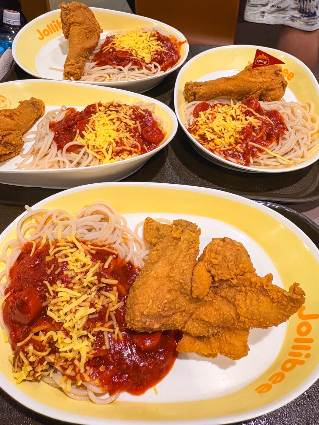 ジョリビーのテーブルに並んだスパゲッティとフライドチキン5皿