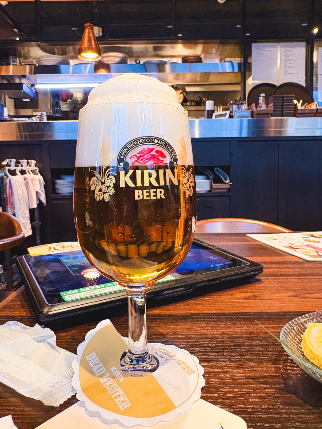A beer with a thick foam head on the counter at Kirin City