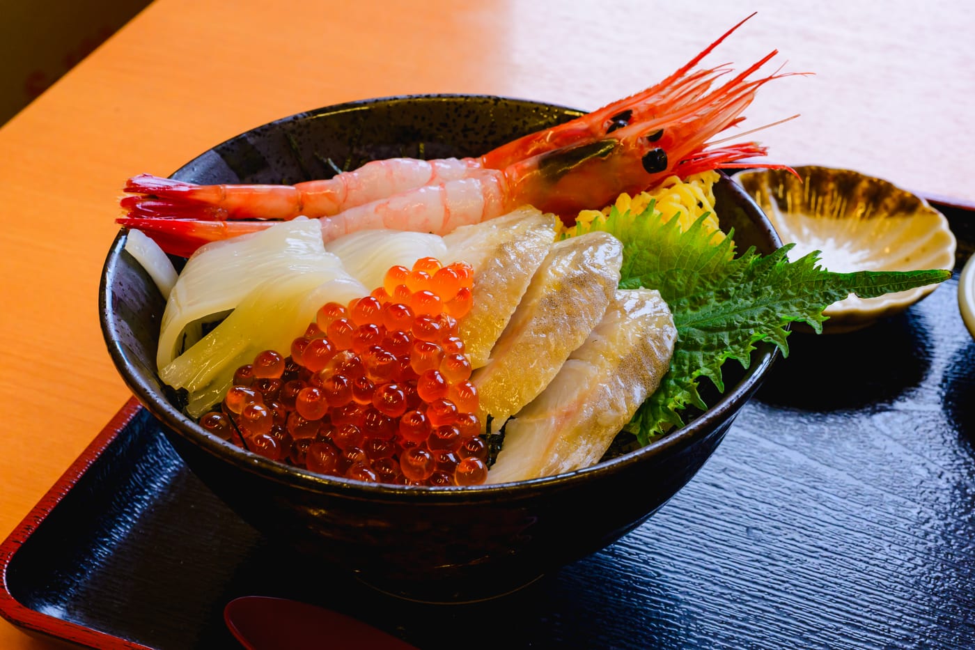 A seafood rice bowl topped with shrimp, tuna, salmon roe, white fish, and other seafood at Hakodate Morning Market