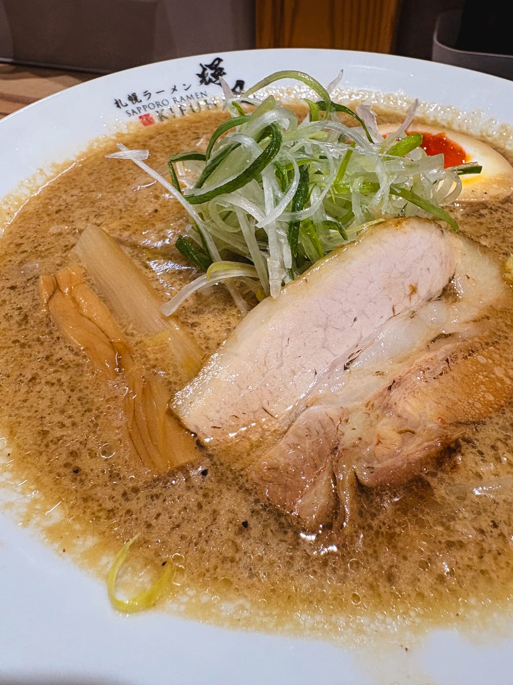 Ramen topped with a seasoned egg, chashu, and green onions at Sapporo Ramen Kifu