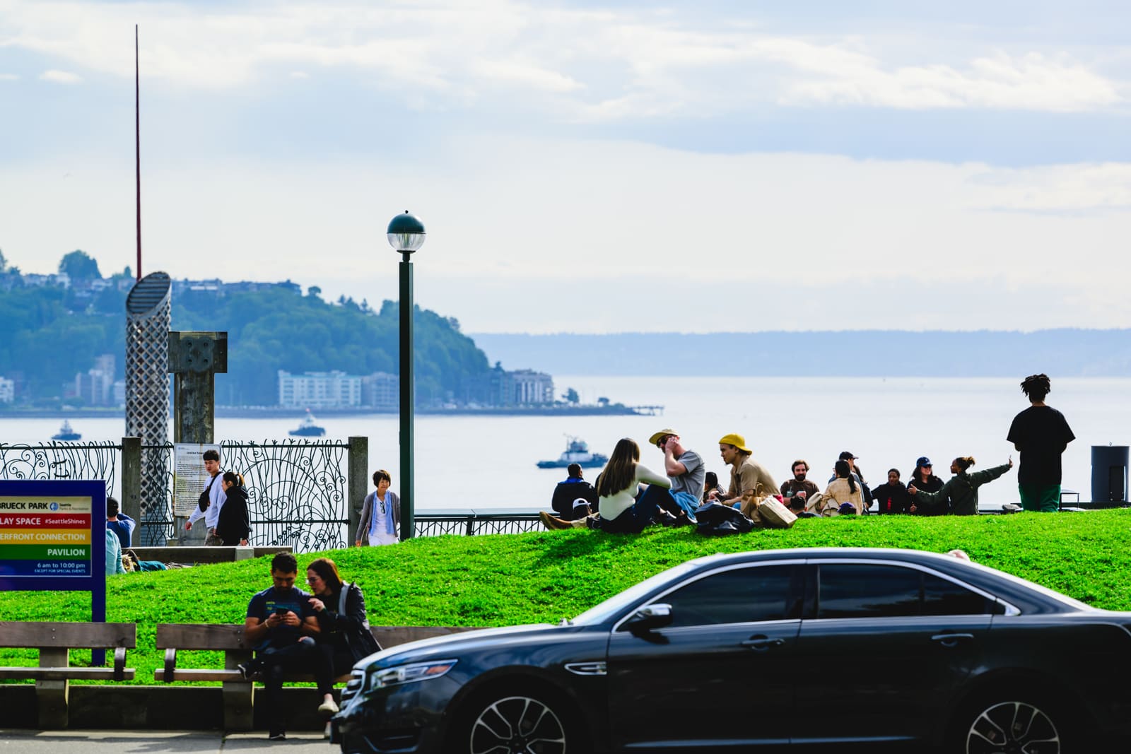 Victor Steinbrueck Park の芝生に座って Elliott Bay を眺める人たち