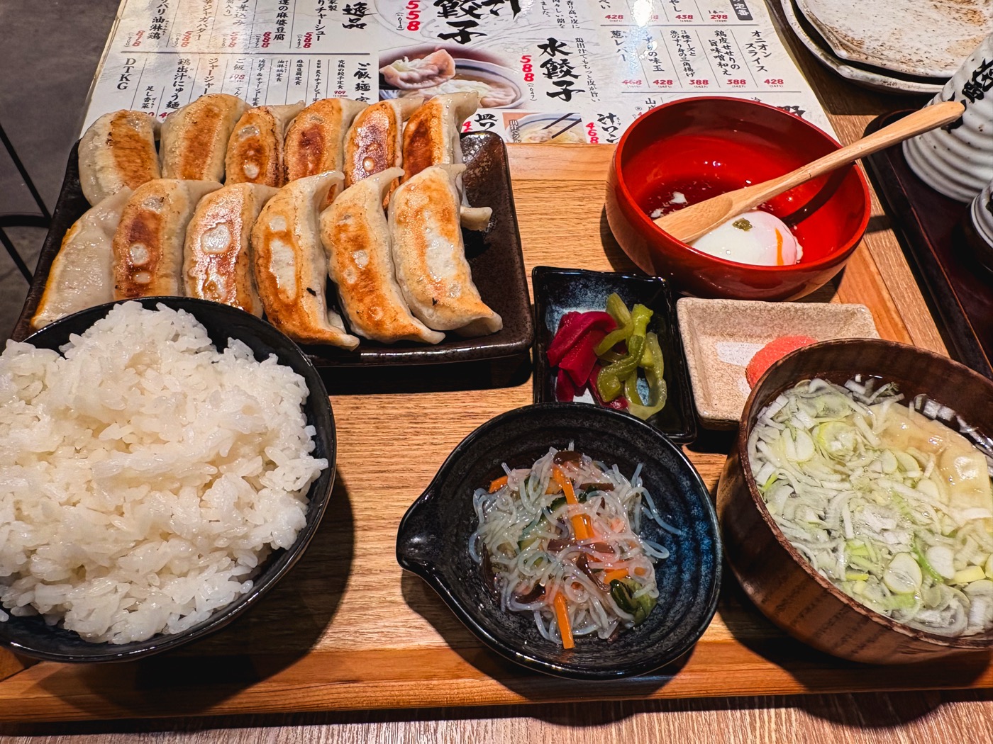 Juicy gyoza on a hot plate with rice, soup, and side dishes
