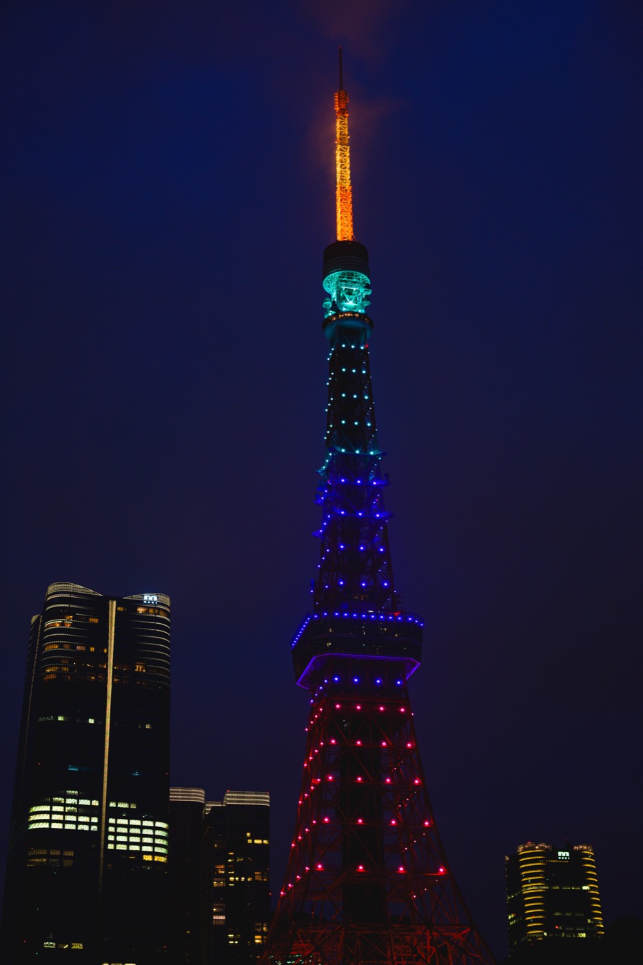 Tokyo Tower illuminated in orange, green, blue, purple, and pink