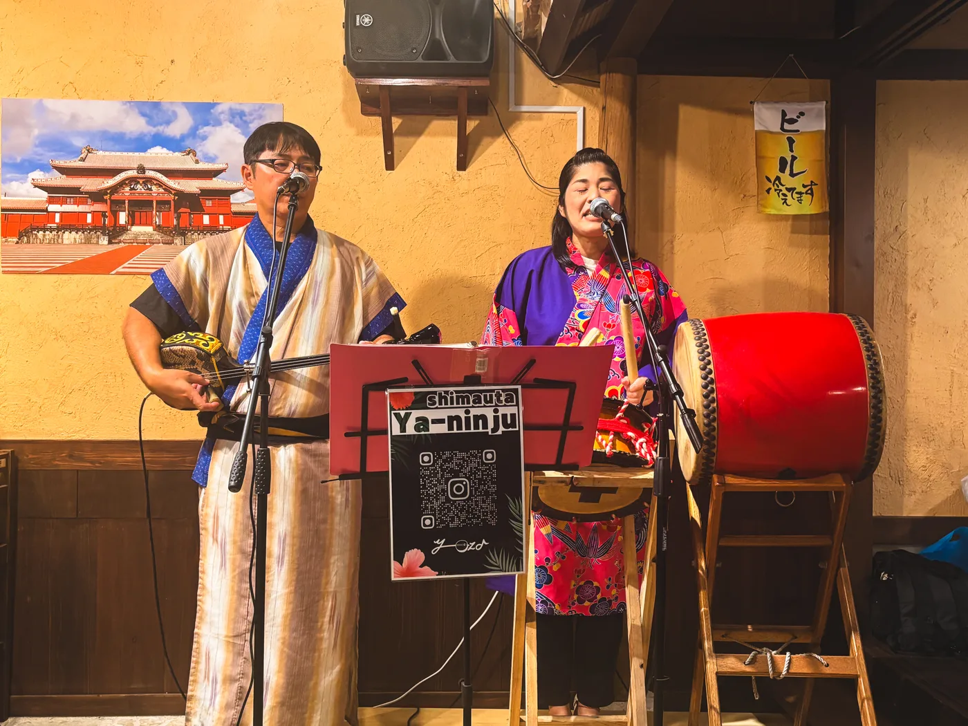 A live folk music performance at Hanaryukyu with a sanshin and microphone