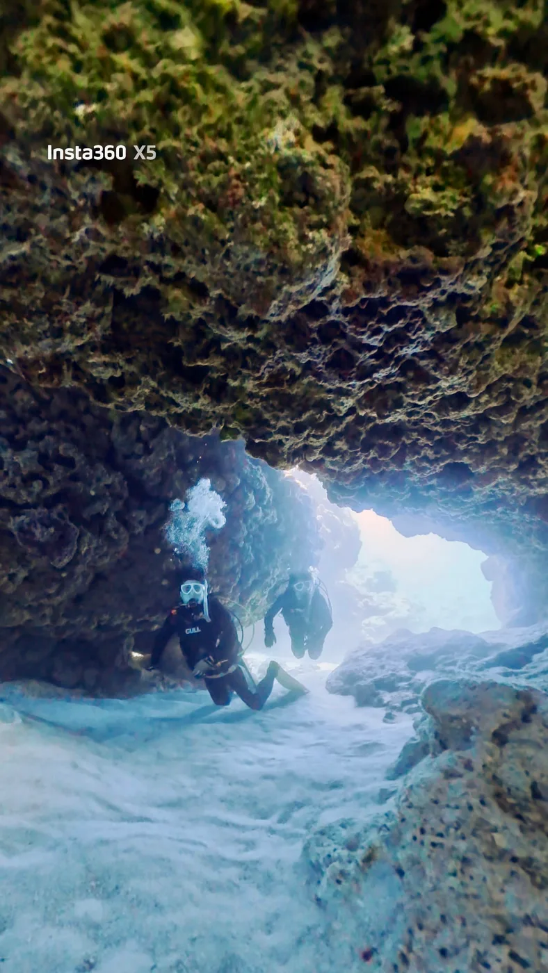 A diver visible through a rock arch