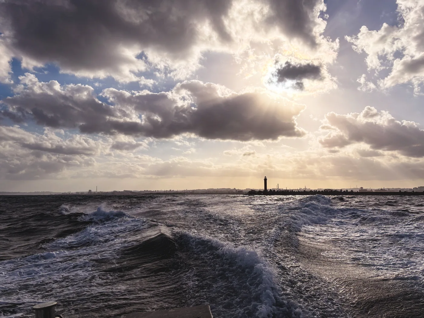 A boat's wake across the sea on a cloudy morning