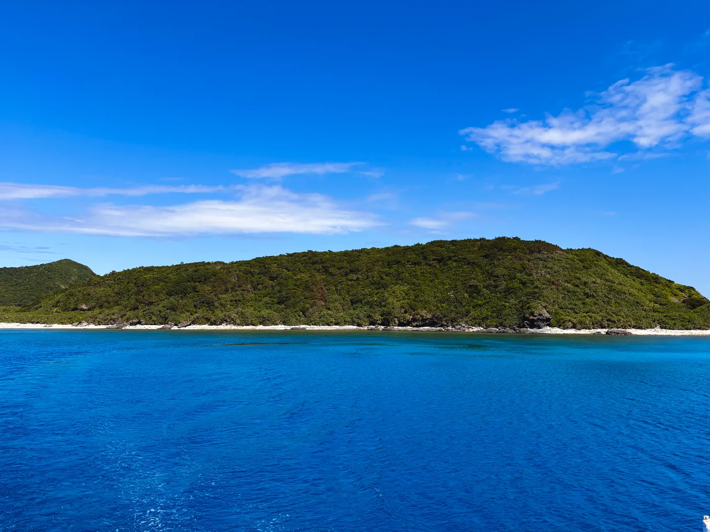 An island shoreline and blue sea beneath a clear sky