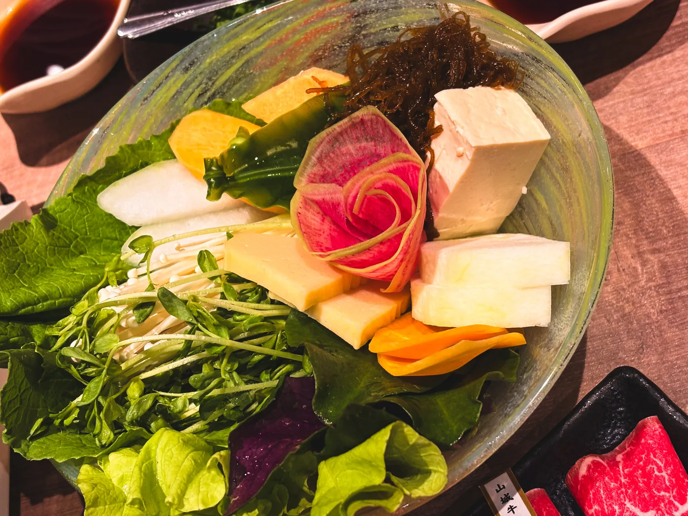 A platter of leafy vegetables, root vegetables, and tofu