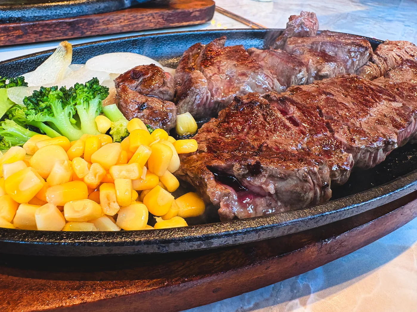 Steak, corn, and broccoli served on a hot plate