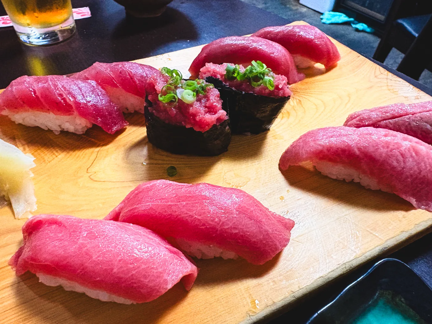 Tuna nigiri and gunkan sushi lined up on a wooden board