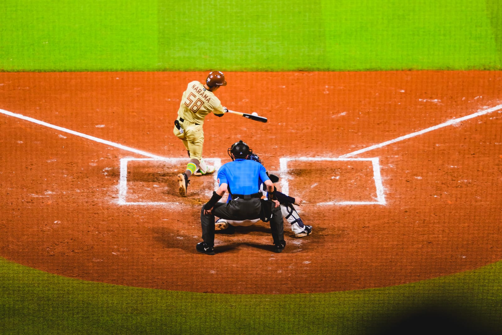 Fighters player Daiki Narama swinging at the plate through the backstop net