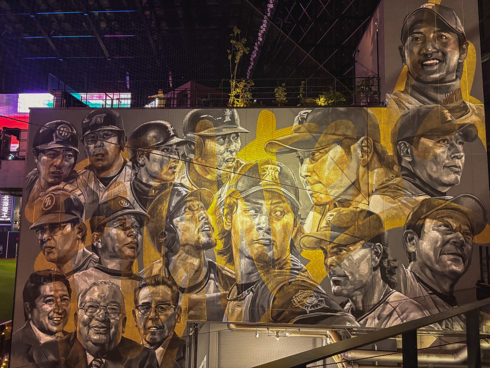 A mural of players from throughout Fighters history on a wall at ES CON FIELD HOKKAIDO