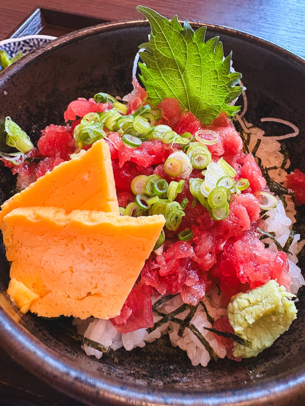 A tuna bowl topped generously with tuna, green onion, and tamagoyaki
