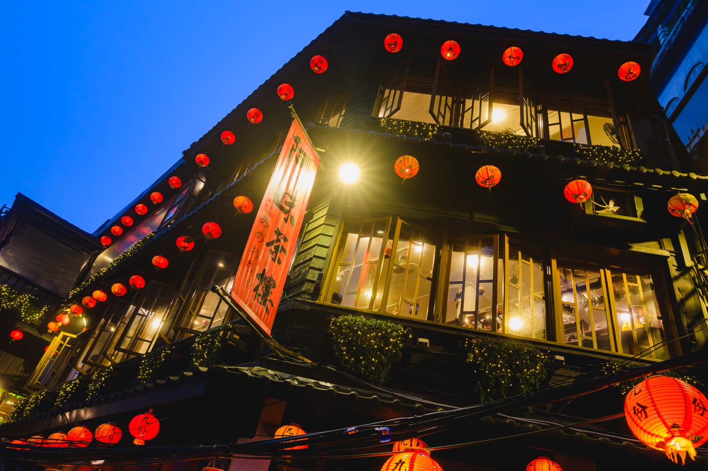 A-MEI Tea House in Jiufen, lit by lanterns beneath the evening sky