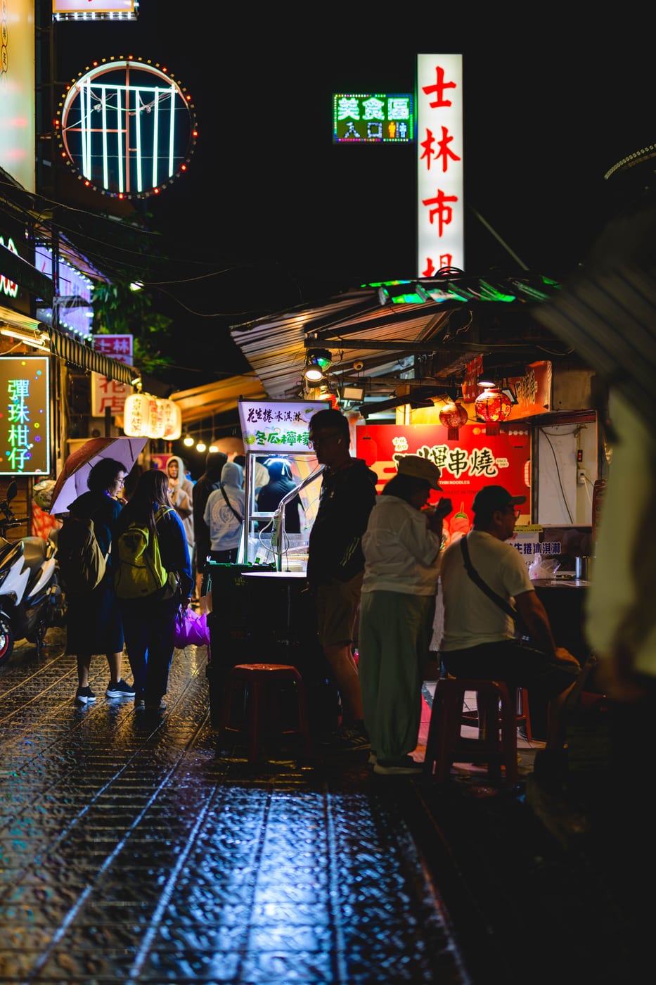 Signs and food stalls lined up at Shilin Night Market at night