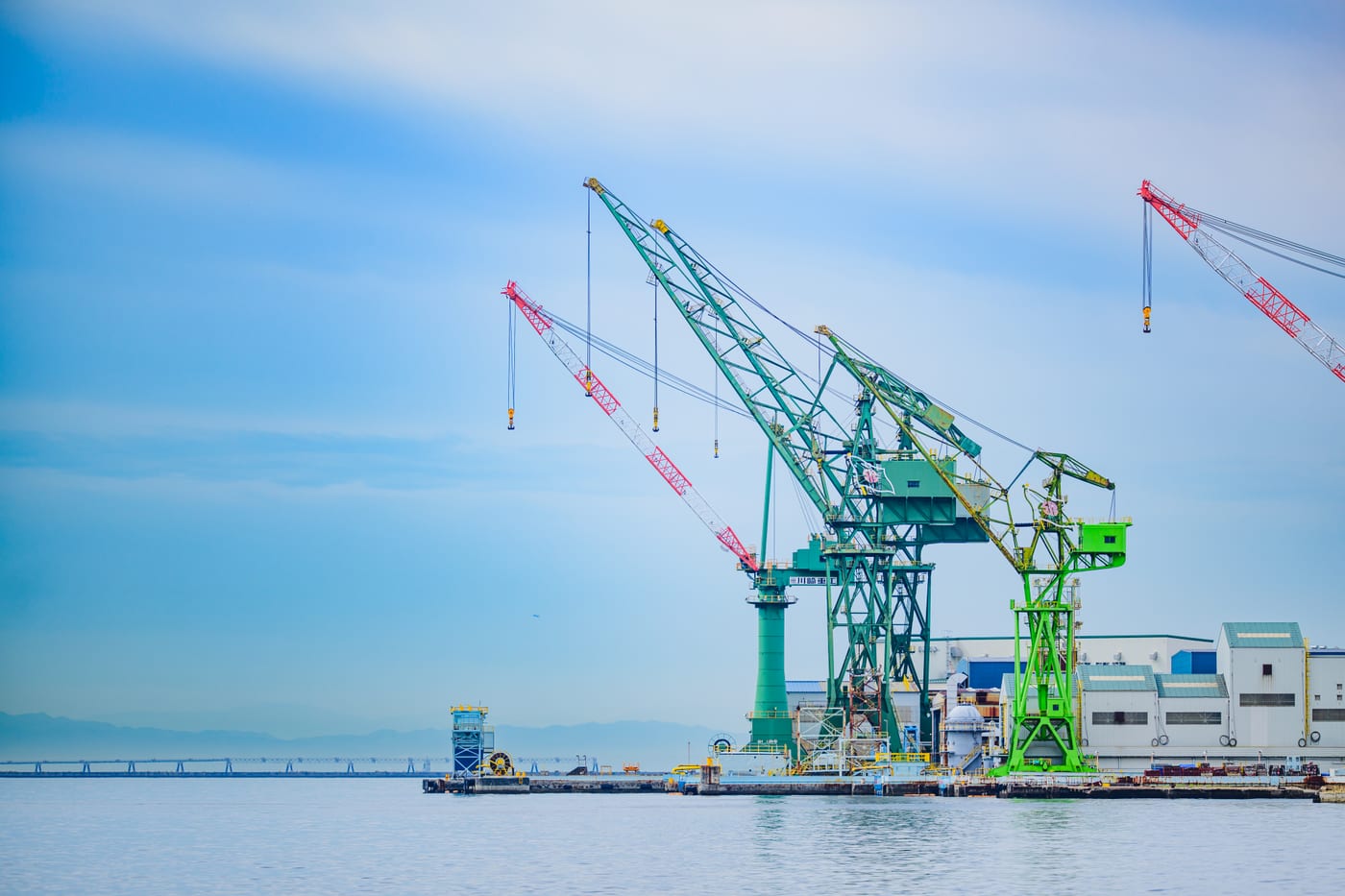 Large green and red cranes lined up across Kobe Port