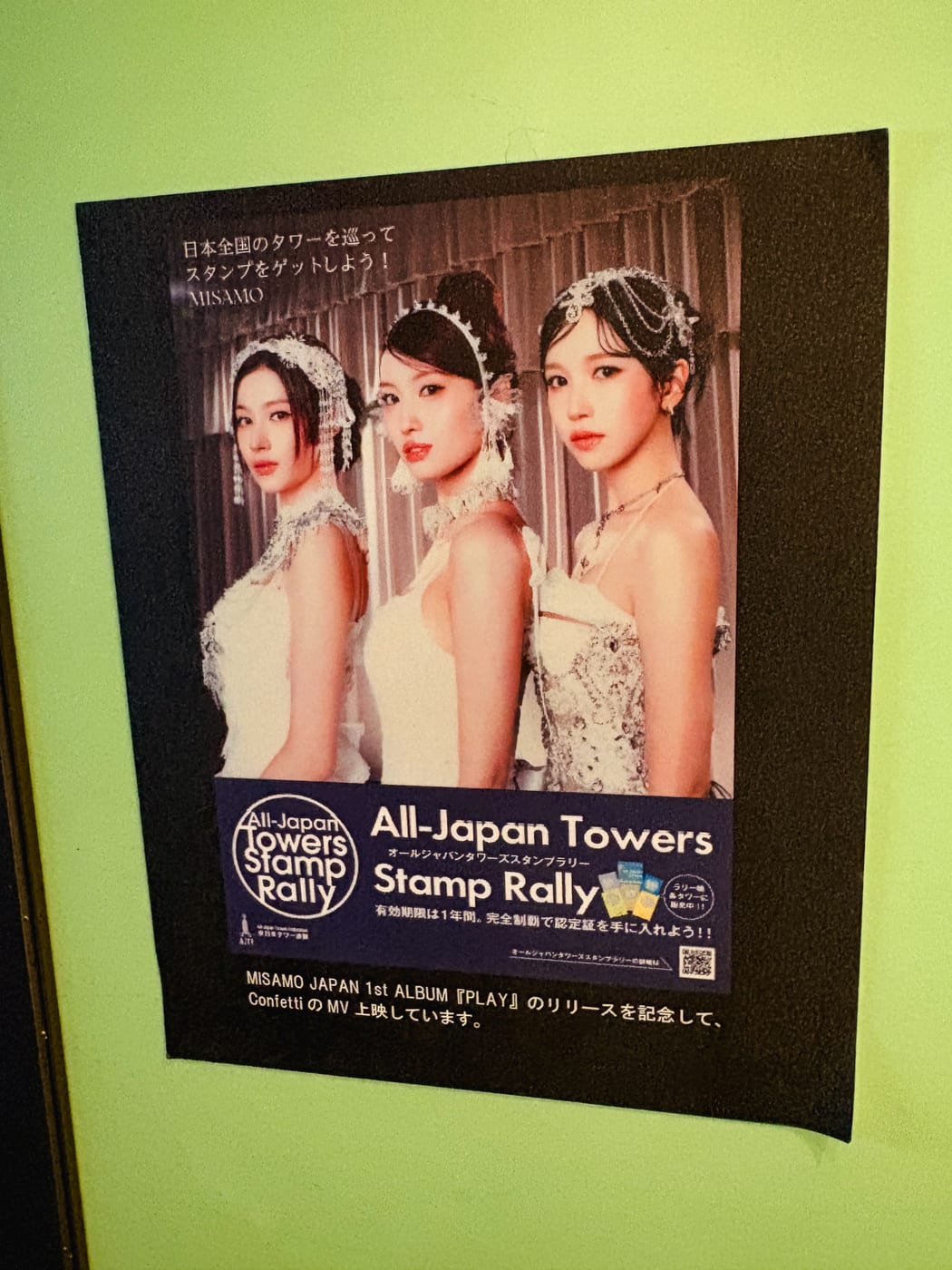 A display featuring the three members of MISAMO and information about the All-Japan Towers Stamp Rally