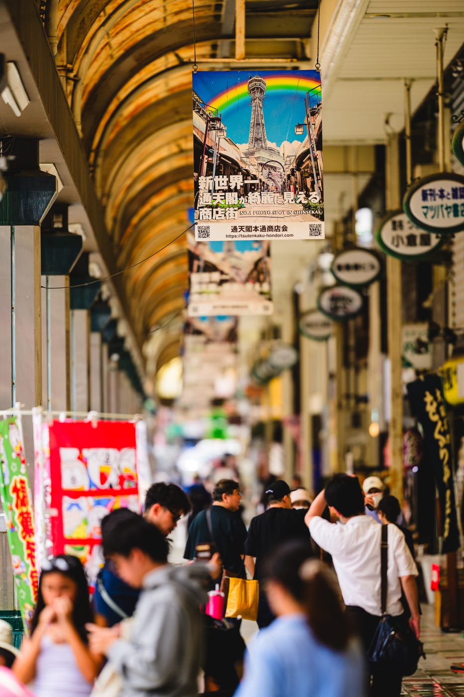 A narrow Shinsekai street crowded with signs and shop curtains