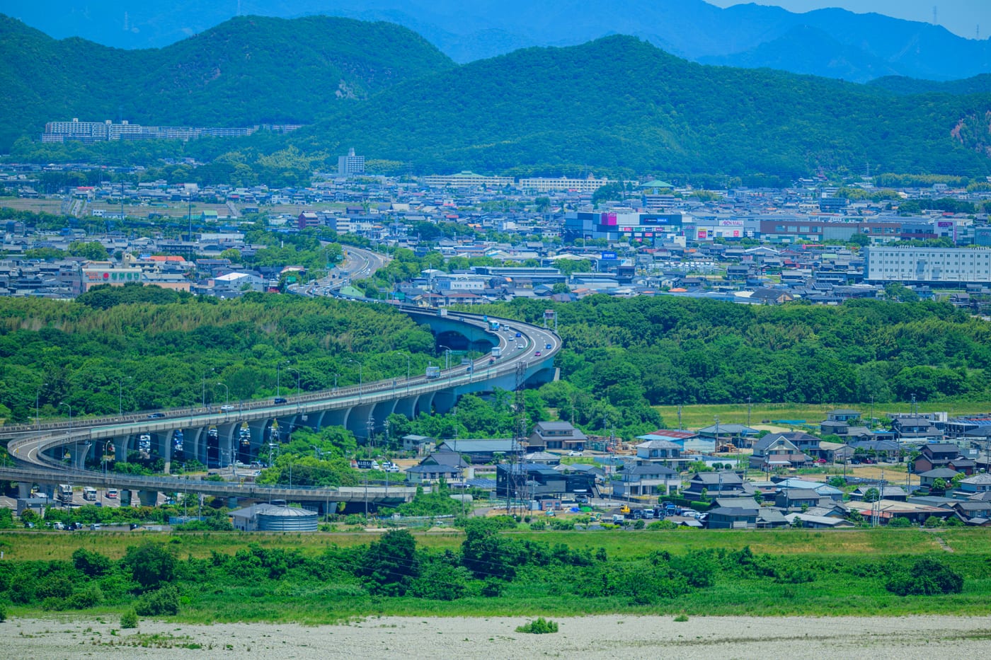 An elevated highway curving through greenery and nearby city blocks