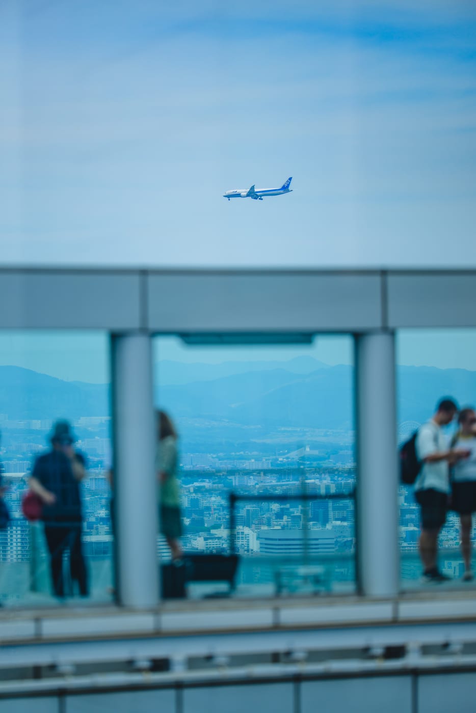 An airplane and the city of Osaka seen through a window at Umeda Sky Building
