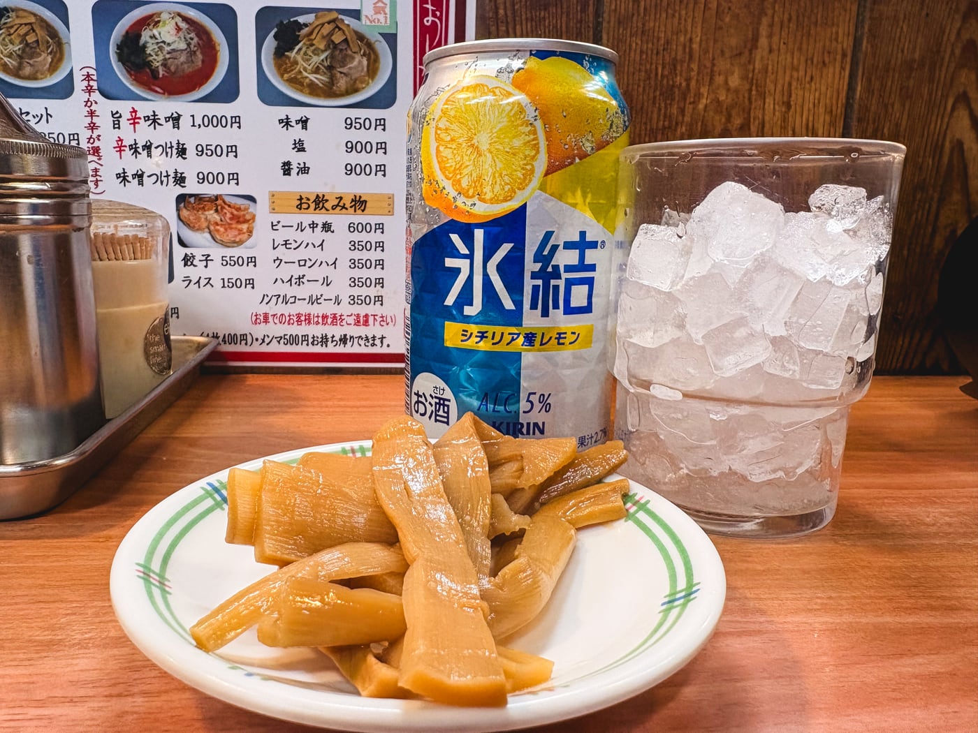 A lemon sour and a plate of menma on the counter at Ezogiku