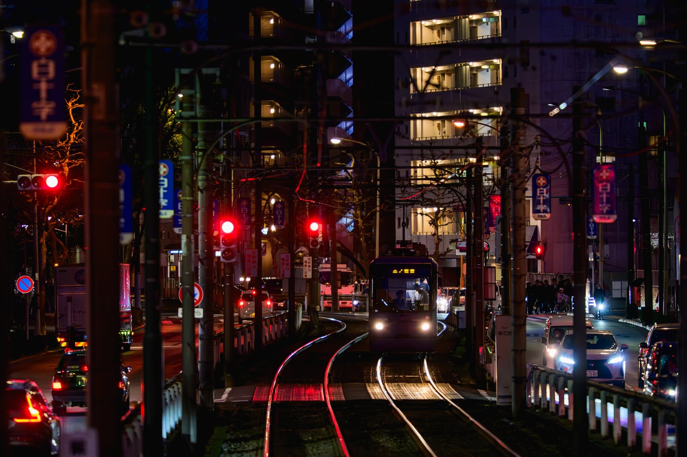 A Tokyo Sakura Tram surrounded by the lights of buildings and cars at night