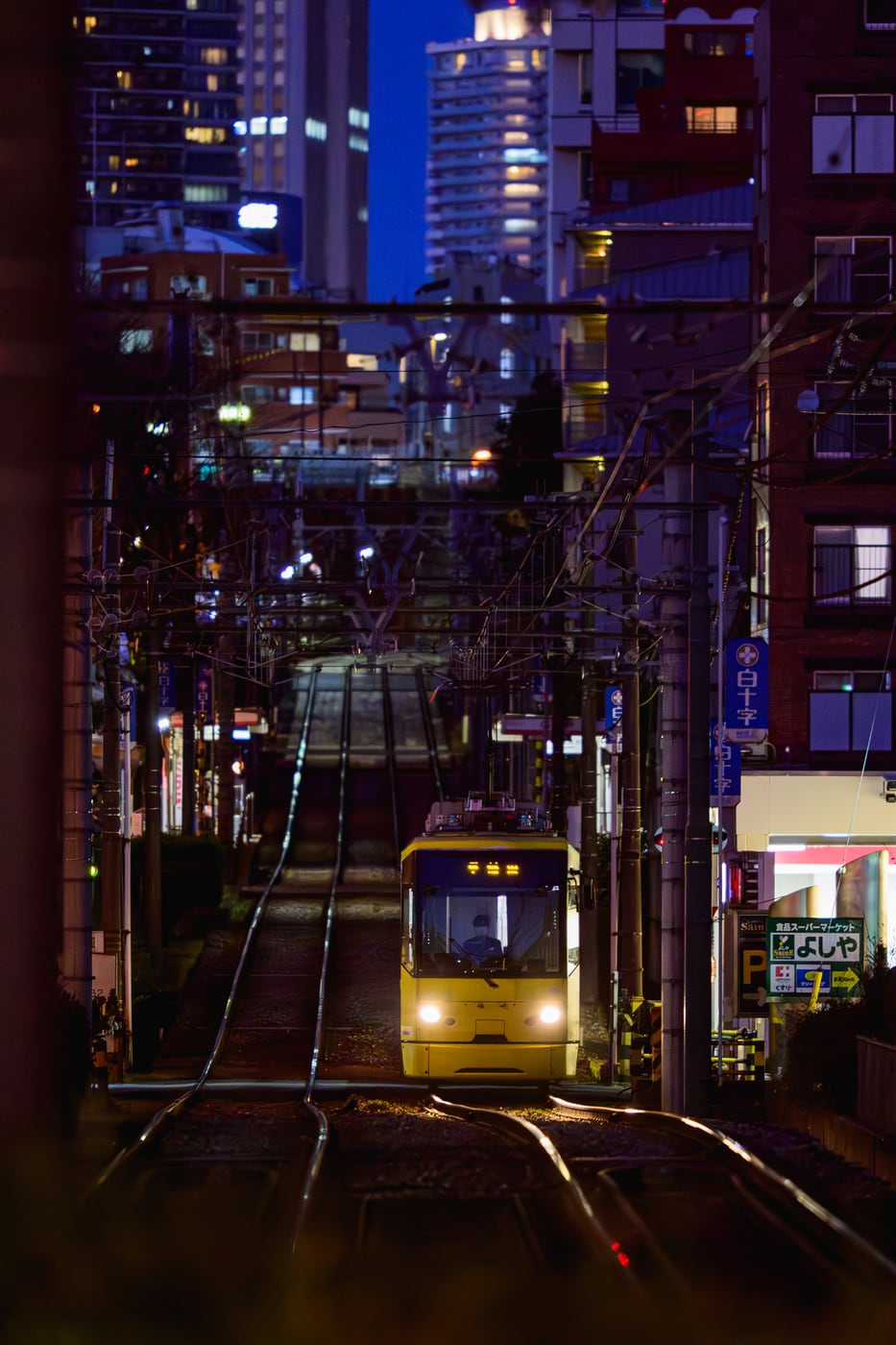 A tram traveling along the slope at night, with light reflecting from the curved rails